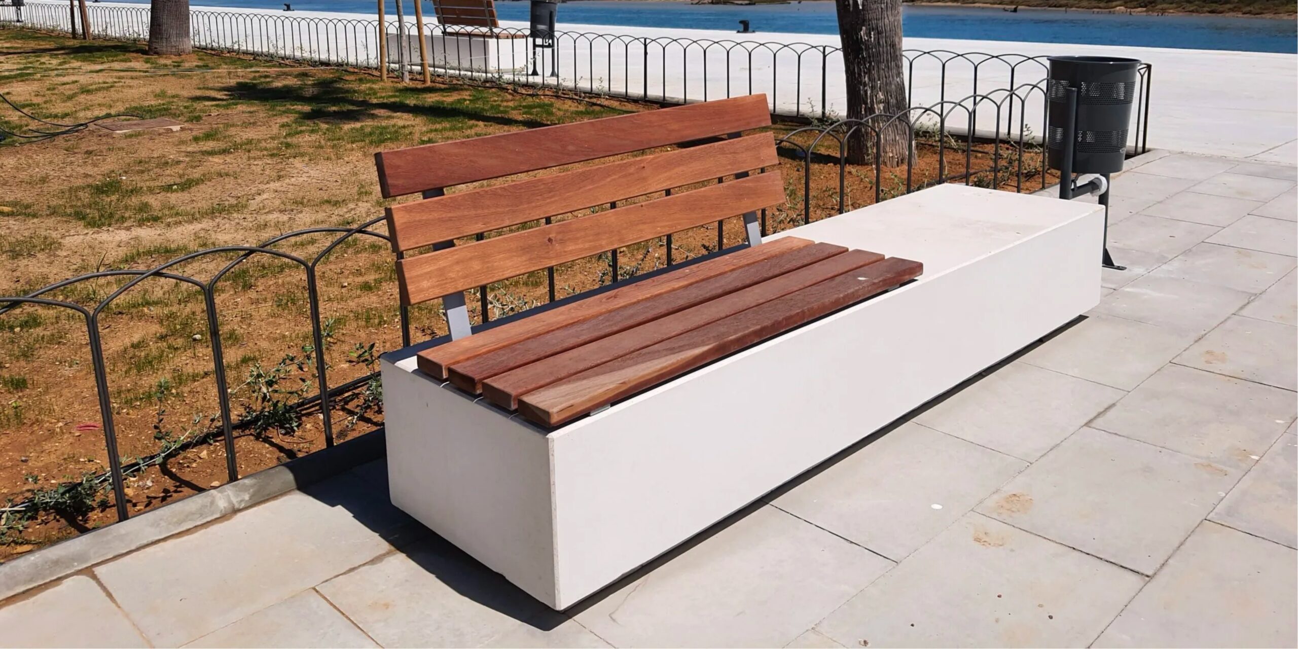 Banco urbano de hormigón con asiento y respaldo de madera.
