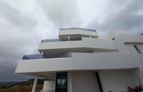 Vivienda unifamiliar con terrazas y pilares, destacando elementos arquitectónicos modernos.