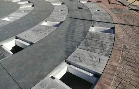 Pavimento de hormigón con aberturas para instalar una fuente circular.