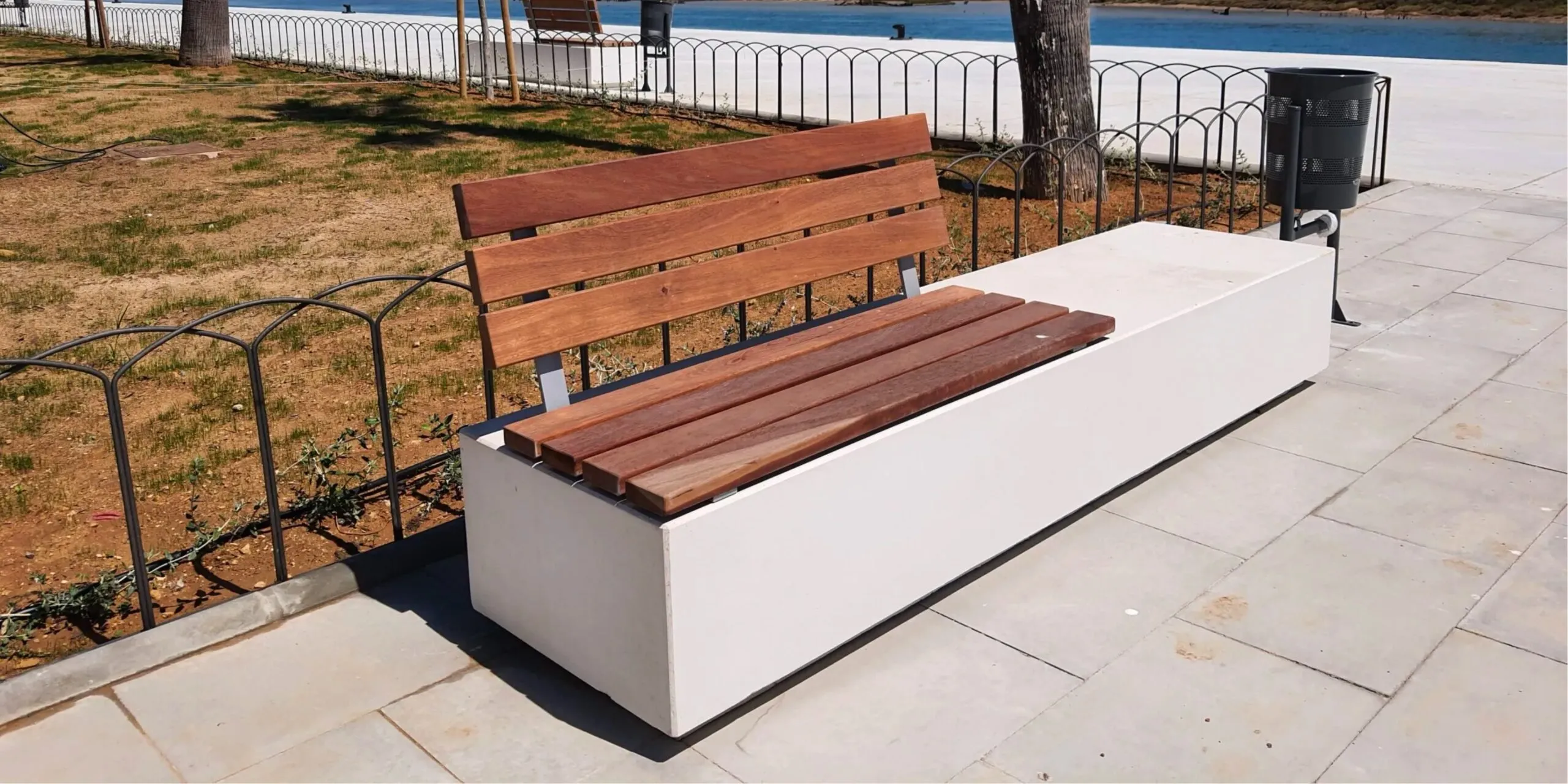 Banco urbano de hormigón con asiento y respaldo de madera.